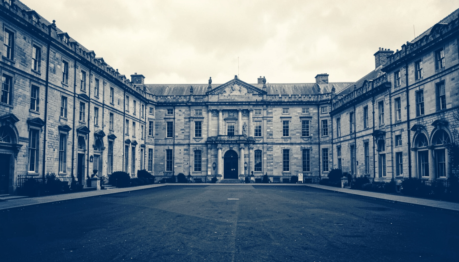 A grand university quadrangle with old stone buildings under a soft overcast sky, muted greys and warm sandstone tones, rendered as a hard two-tone duotone in deep blue and ivory.